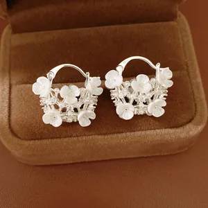 Detailed macro view of elegant zircon flower basket earrings with pearls and white blossoms