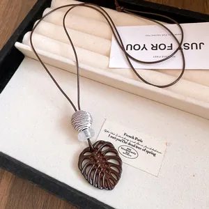 Détail du collier avec pendentif feuille de Monstera et cordon en cuir marron