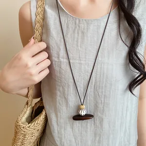 Vue détaillée d'un collier long avec pendentif en bois et résine sur lin gris