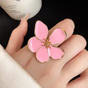Macro close-up view of an oversized pink enamel flower ring with gold-tone adjustable band