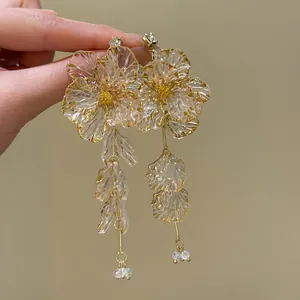 Detailed view of handmade acrylic flower tassel earrings with gold edging and studs