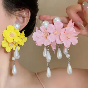Close-up of floral fabric earrings with elegant teardrop pearl tassels and round studs.