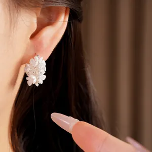 Elegant macro view of sweet flower earrings with zircon and pearls worn on an ear