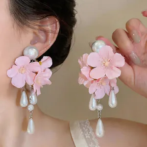 Close-up detail of pink fabric flower earrings with elegant teardrop pearl tassels.