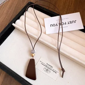 Vue détaillée d'un collier avec pendentif en résine sur un plateau de présentation.