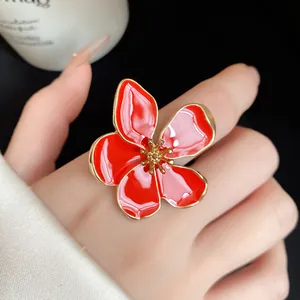Detail macro view of a vibrant red enamel flower statement ring with elegant gold edges.