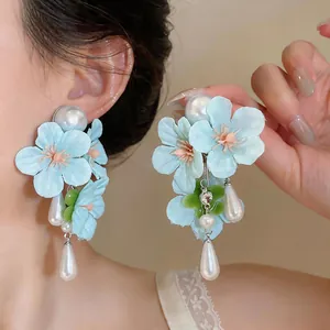 Detail view of light blue fabric flower earrings featuring elegant teardrop pearl tassels.