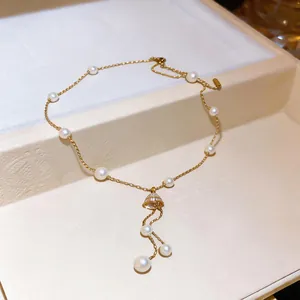 Detailed view of 18K gold plated pearl necklace with shimmering zircon bell pendant detail