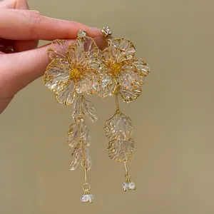 Close-up of translucent acrylic flower tassel earrings with delicate crystal accents.