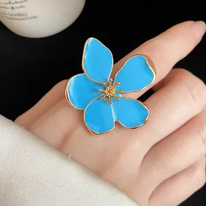 Close-up of oversized blue enamel flower ring with golden edges and pistil detail.