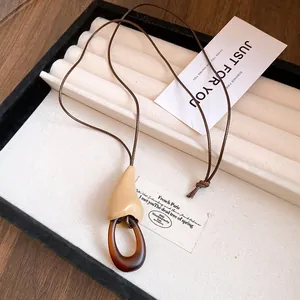 Détail d'un collier avec pendentif en résine et bois posé sur un plateau à bijoux
