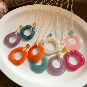 Detailed close-up of colorful resin ring necklaces with cords displayed on a white plate.