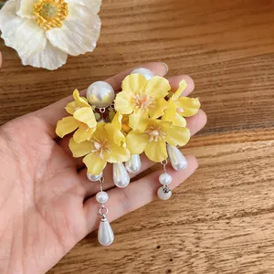 Detailed view of handmade yellow fabric flower earrings with elegant white pearl tassels.