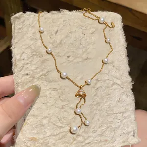 Detail shot of 18K gold-plated pearl necklace with a bell pendant and zircon accents
