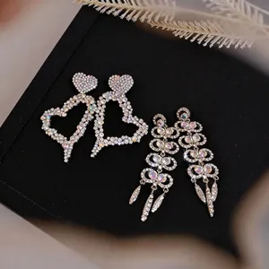 Elegant rhinestone hollow heart and geometric dangle earrings on luxury black display stand