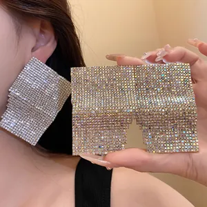 Close-up macro view of oversized square silver rhinestone earrings on model's ear