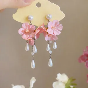 Detail showing pink fabric flower earrings with elegant white pearl teardrop tassels