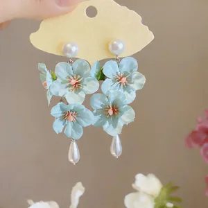 Close-up of light blue fabric flower earrings with elegant pearl teardrop tassels