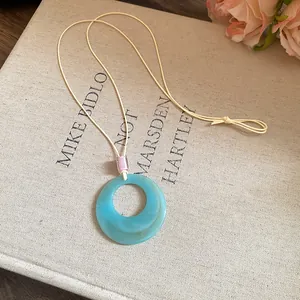 Detailed view of the blue resin donut pendant featuring a subtle marble texture on a beige cord