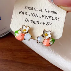 Vista dettagliata di orecchini a lobo fragola con fiore bianco e ago in argento S925 per donna