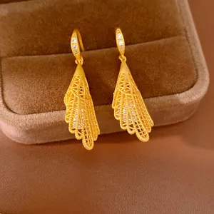 Gros plan de boucles d'oreilles pendantes en dentelle dorée avec des zircons