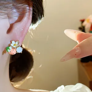 Primo piano di orecchini a lobo con fragola e fiori indossati sull'orecchio