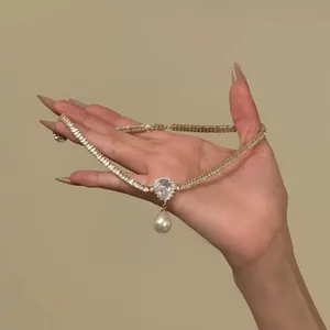 Elegant stainless steel choker with heart-shaped stone and pearl drop held in hand