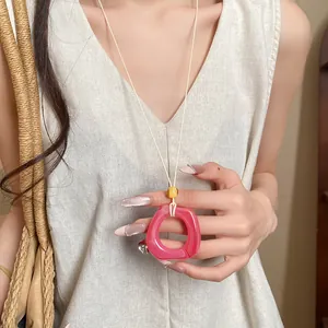 Detail view of a pink resin geometric ring pendant on a minimalist cream string necklace