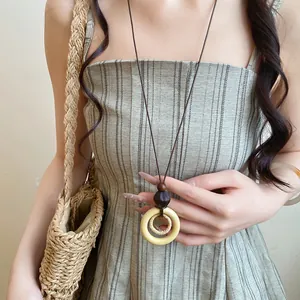 Détail d'un collier vintage avec un pendentif circulaire en bois et résine sur cordon en cuir