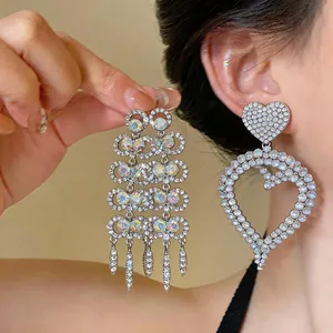 Close-up detail of silver crystal heart and fringe drop earrings on a model.