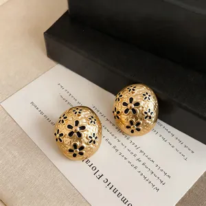 Detailed view of French vintage gold oval stud earrings with black flower enamel.