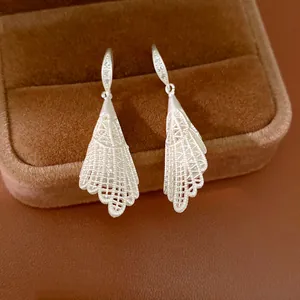 Gros plan détaillé de boucles d'oreilles pendantes en dentelle argentée avec zircon.