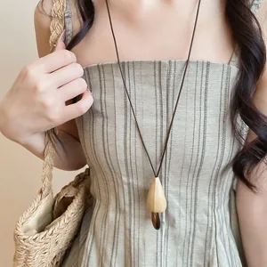 Détail d'un collier pendentif champignon en bois et résine sur cordon en cuir.