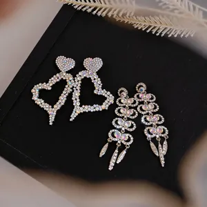 Close-up of sparkling silver needle rhinestone hollow heart and long tassel earrings