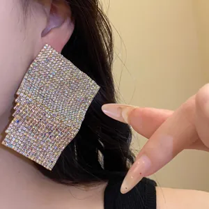 Detailed close-up of sparkling iridescent rhinestone geometric square stud earrings on ear