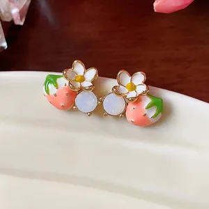 Vista macro dettagliata di orecchini a lobo con fragole e fiori placcati in oro 18k