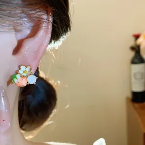 Dettaglio ravvicinato di un orecchino a perno con fragola e fiore placcato oro 18 carats.