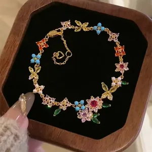 Macro detail of 18k gold plated bracelet featuring colorful zircon flowers and butterflies