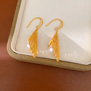 Vue détaillée de boucles d'oreilles en filigrane d'or avec perles blanches dans un écrin.