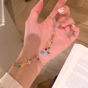 Elegant detail of a gold-plated bracelet featuring multicolored zircon flowers and butterflies