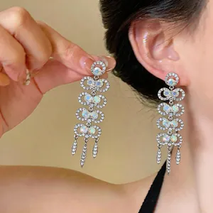Detailed view of silver dangling earrings with rhinestones and iridescent stones