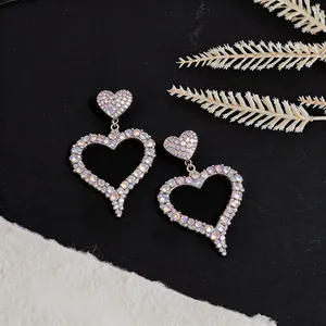 Detailed view of hollow heart-shaped earrings with iridescent pavé rhinestones