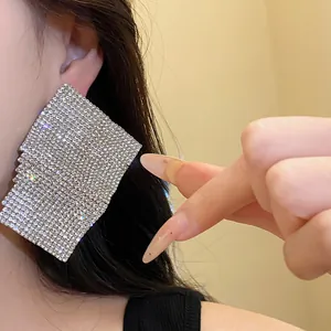 Close-up detail of large square rhinestone stud earrings worn on ear for elegant look