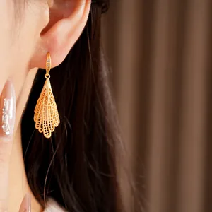 Vue détaillée de boucles d'oreilles pendantes en dentelle dorée serties de zircons.