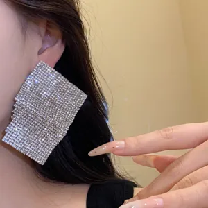 Detailed view of an Asian model wearing oversized luxury square rhinestone stud earrings