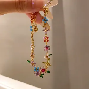 Detailed close-up of an 18k gold-plated bracelet with zircon flowers and pearls.