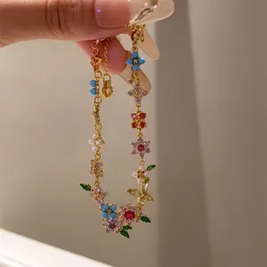 Detailed close-up of a floral zircon and pearl bracelet with 18k gold plating finish.