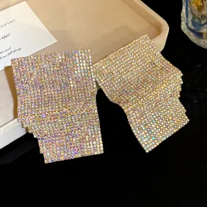 Close-up detail of geometric square stud earrings with shimmering iridescent rhinestones