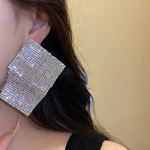Close-up of oversized geometric square earrings with sparkling rhinestones on model