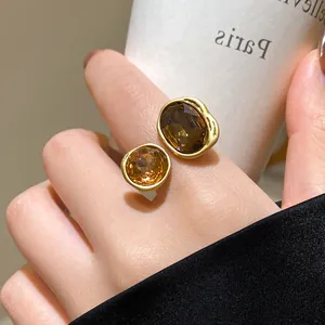 Macro shot of a vintage-style gold ring with amber and brown faceted gemstones on a finger.
